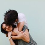 A loving couple shares a joyful embrace against a light background outdoors.
